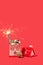Miniature house with shiny golden Christmas balls and sparklers on red background. New Year or Christmas glowing decoration idea