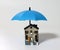 A miniature old couple sitting on a blue umbrella and a miniature house.