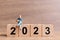 Miniature people , A businessman is seated on a wooden block 2023