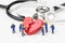 Miniature people cute technician workers team with uniform help fixing or repair red broken heart with stethoscope on white