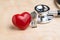Miniature people elderly senior retired couple with doctor`s stethoscope and shinny red heart on wooden table, health care,