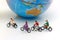 Miniature people enjoy riding a bicycle with globe