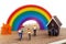 Miniature people enjoy riding a bicycle with home and rainbow