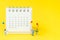 Miniature people figures happy family holding balloons standing with white clean desktop calendar on solid yellow background with