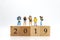 Miniature people, group travelers standing on wooden block 2019, new year. Image use for travel business concept.