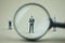 Miniature people: Magnifying glass focusing on the selection of executive businessman, recruitment process