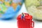 Miniature people : man sitting on red suitcase with mini global