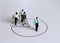 Miniature people standing on a circle graph.