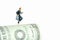 Miniature people toy figure photography. School admission budget concept. Young girl pupil running above rolled dollar money paper