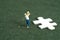 Miniature people toy figure photography. Winning tournament concept. A men golfer standing beside puzzle jigsaw at meadow field