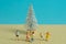 Miniature people toy figure photography. Winter playtime concept. Kids play together in front of white fir tree