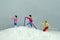 Miniature people toy figure photography. Winter sport. Group of women go on a trekking on snowy mountain at cloudy weather