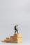 Miniature people traveller standing on wooden block on gray background