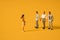 Miniature people on a yellow background, men against women at work. The concept of gender equality, feminism