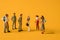 Miniature people on a yellow background, men against women at work. The concept of gender equality, feminism