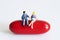Miniature peoples on red capsule