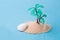 miniature plastic palm tree in the sand, blue background