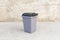 miniature plastic trash container on a gray concrete background