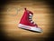 Miniature red baskeball shoe on wooden floor as background