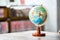 A miniature replica of the globe is placed on wooden table beside bookshelf in the library