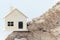 Miniature replica wooden house is located on a sand pile.