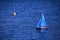 Miniature sailboat and yellow buoy on rippled blue sea