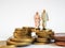 Miniature senior couple stand on pile of Euro coins. Retirement
