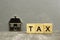 Miniature Small metal house and the word Tax, concept