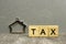 Miniature Small metal house and the word Tax, concept