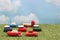 Miniature toy cars on green grass over blue sky and clouds.