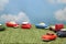 Miniature toy cars on green grass over blue sky and clouds.