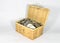 Miniature wicker chest filled with different coins on white background, saving money concept