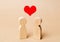 Miniature wooden figures of people and a red heart above them. Concept of love, romantic relationship. Sympathy. A loving couple