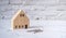 Miniature wooden house with a key on a white brick floor. Insurance, mortgage, trading, home brokerage, housing needs. House
