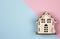 Miniature wooden house on a pink and blue graphic background, top view. Concept mortgage, purchase, sale, rental property