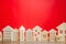 Miniature wooden houses on a red background. Real estate concept. City. Agglomeration and urbanization. Market Analytics. Demand