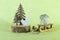 miniature wooden sledge carrying a small gift next to a decorative Christmas tree made of wood with a little squirrel on a green