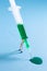 A miniature worker holding a syringe with a green substance in it