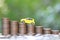 Miniature yellow car model on growing stack of coins money on nature green background, Saving money for car, Finance and car loan