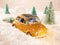 Miniature yellow car with spruce trees