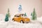 Miniature yellow car with spruce trees