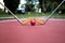 Minigolf iron rackets and a red ball at a court ground.