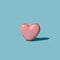 Minimal artisan french patisserie concept. Pink heart shaped yummy irresistible macaron alone against baby blue background