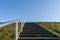 Minimal background with a staircase, green grass field, and clear blue sky