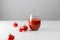 Minimal creative composition with glass glass of tomato juice and tomatoes scattered chaotically on white table