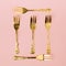 Minimal creative concept of gold forks making square symbol with nice pastel pink background. Celebration idea