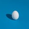 Minimal Easter concept made with white egg on serenity blue background