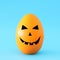 minimal and funny Halloween holiday concept. Orange egg with scary cute face.