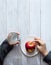 Minimal healthy snack concept. The child`s hands are holding an apple and a glass of water. Still life on a light wooden table wit