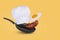 Minimal idea with a frying pan, chef hat, flying fried egg and bacon on a yellow background